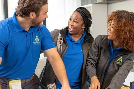 Team members wearing matching custom branded polo shirts and jackets organizing promotional products at a table.