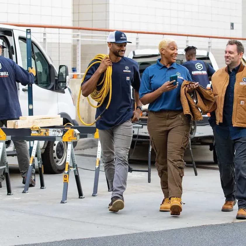 A group of contractors are walking on site with branded t-shirts, polos, and outerwear.